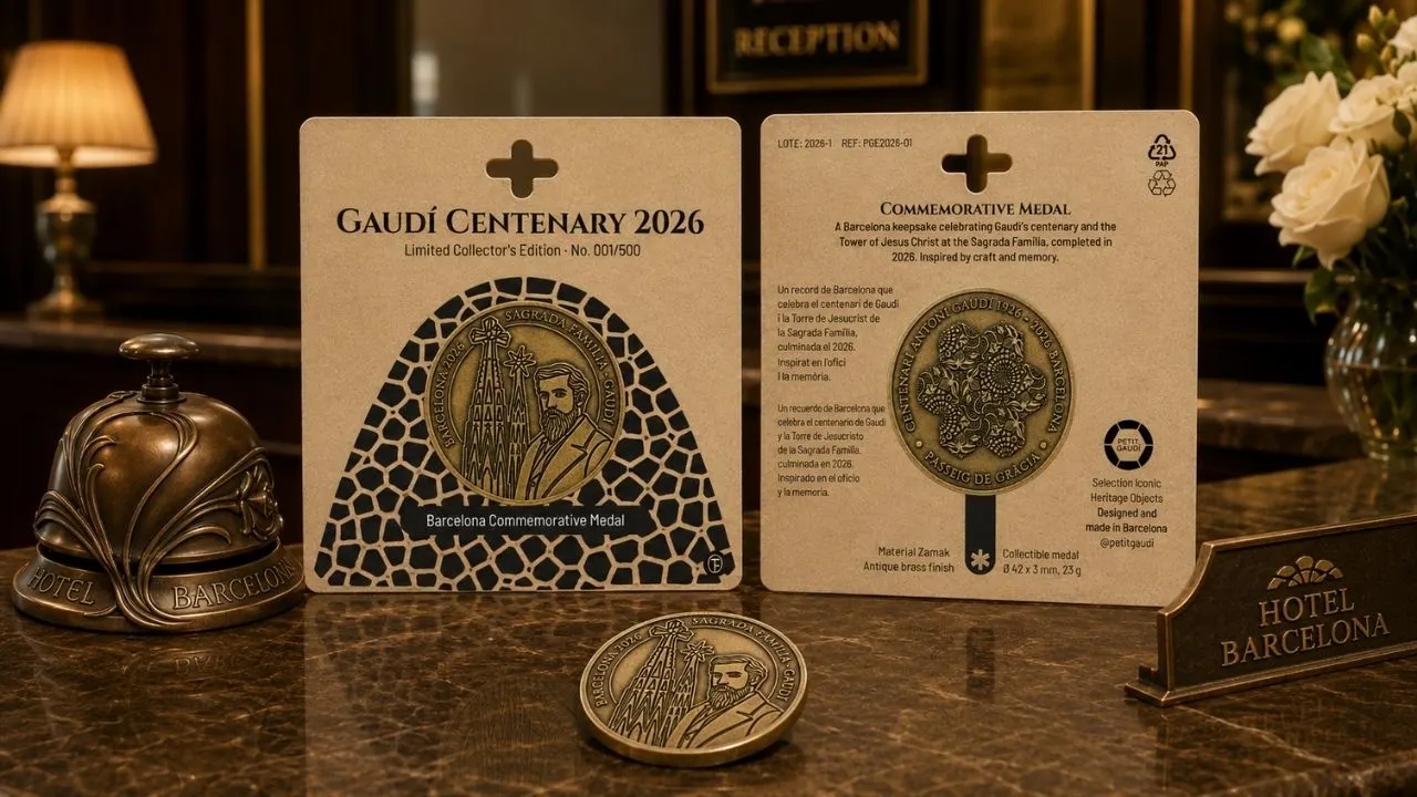 Medalla Gaudí Centenary 2026 en recepción de hotel Medalla conmemorativa Gaudí Centenary 2026 en blister junto a una medalla extra sobre mostrador clásico de hotel.