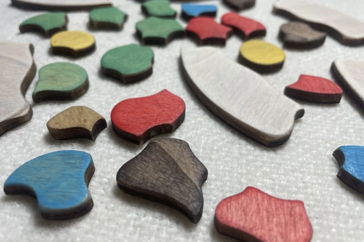 Piezas de madera para pintar Piezas del Puzzle Trencadís pintadas en diferentes colores y distribuidas sobre una mesa