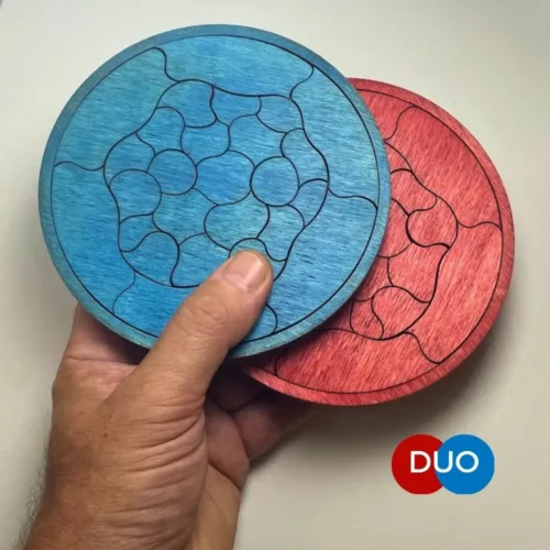 Dos Puzzle Trencadís DUO de madera en azul y rojo sostenidos en la mano