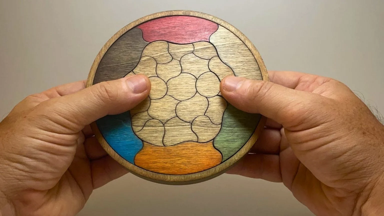Puzzle Trencadís de madera sostenido con las manos con piezas de colores intercambiables