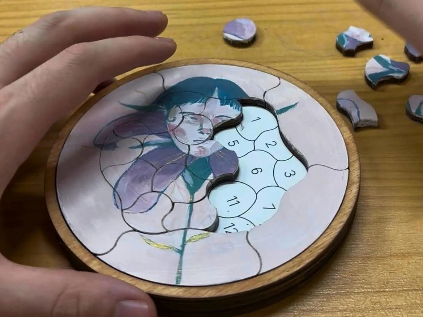 Una mano mueve las piezas de un Puzzle Trencadís con una ilustración impresa sobre la madera.