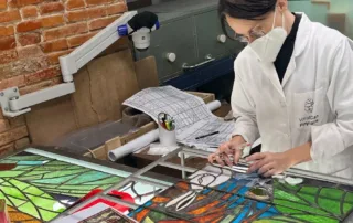 Artesana de Vitralls Can Pinyonaire trabajando en la restauración de una vidriera artística